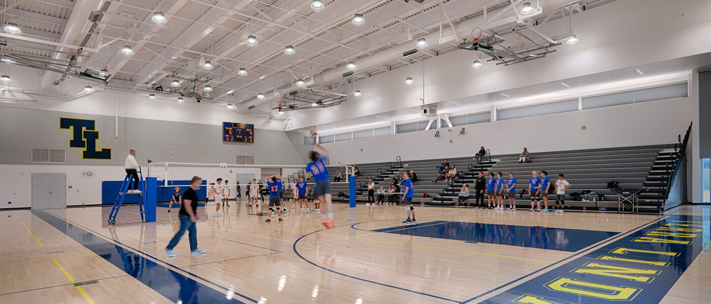Terra Linda's Gymnasium interior. Hardwood floors with blue accents. High ceilings with bright white lights.