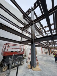 Exterior of building, featuring a scissor lift and steel work columns.