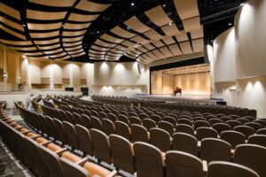 Large, modern auditorium with a grand piano on stage.
