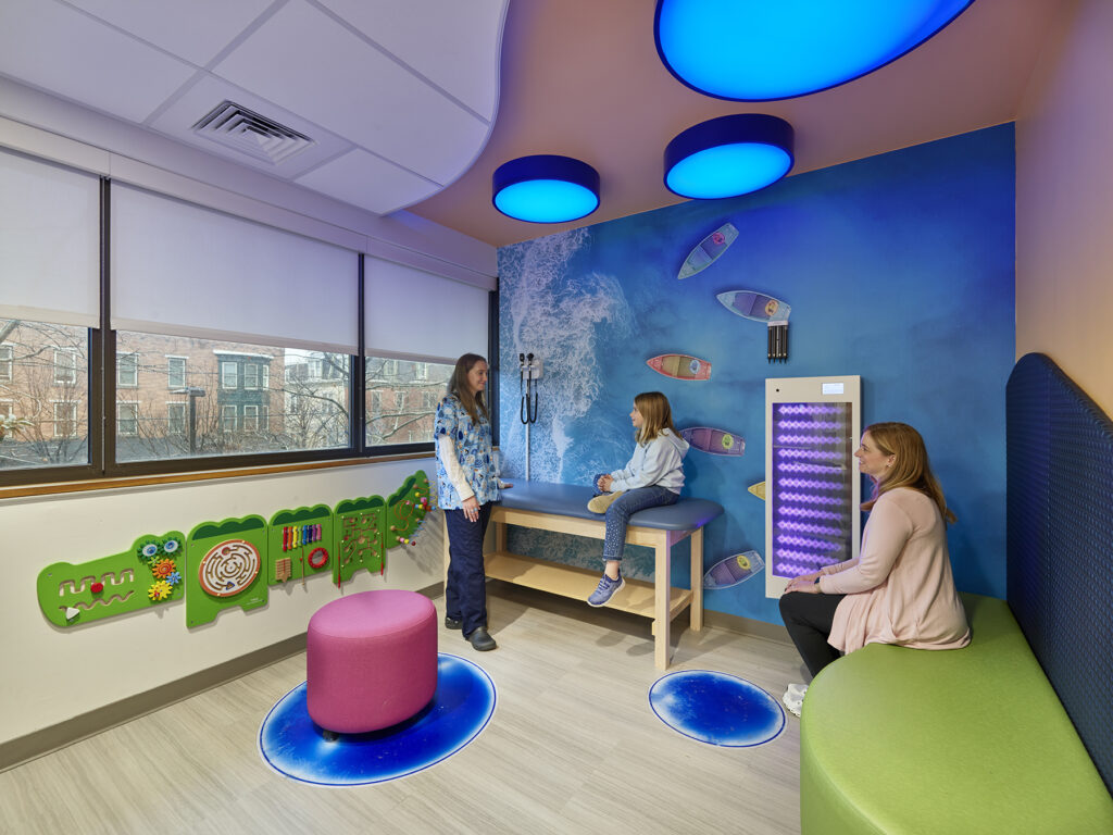 Colorful wellness room with a calming mural of the ocean, large windows, and comfortable spaces to sit.