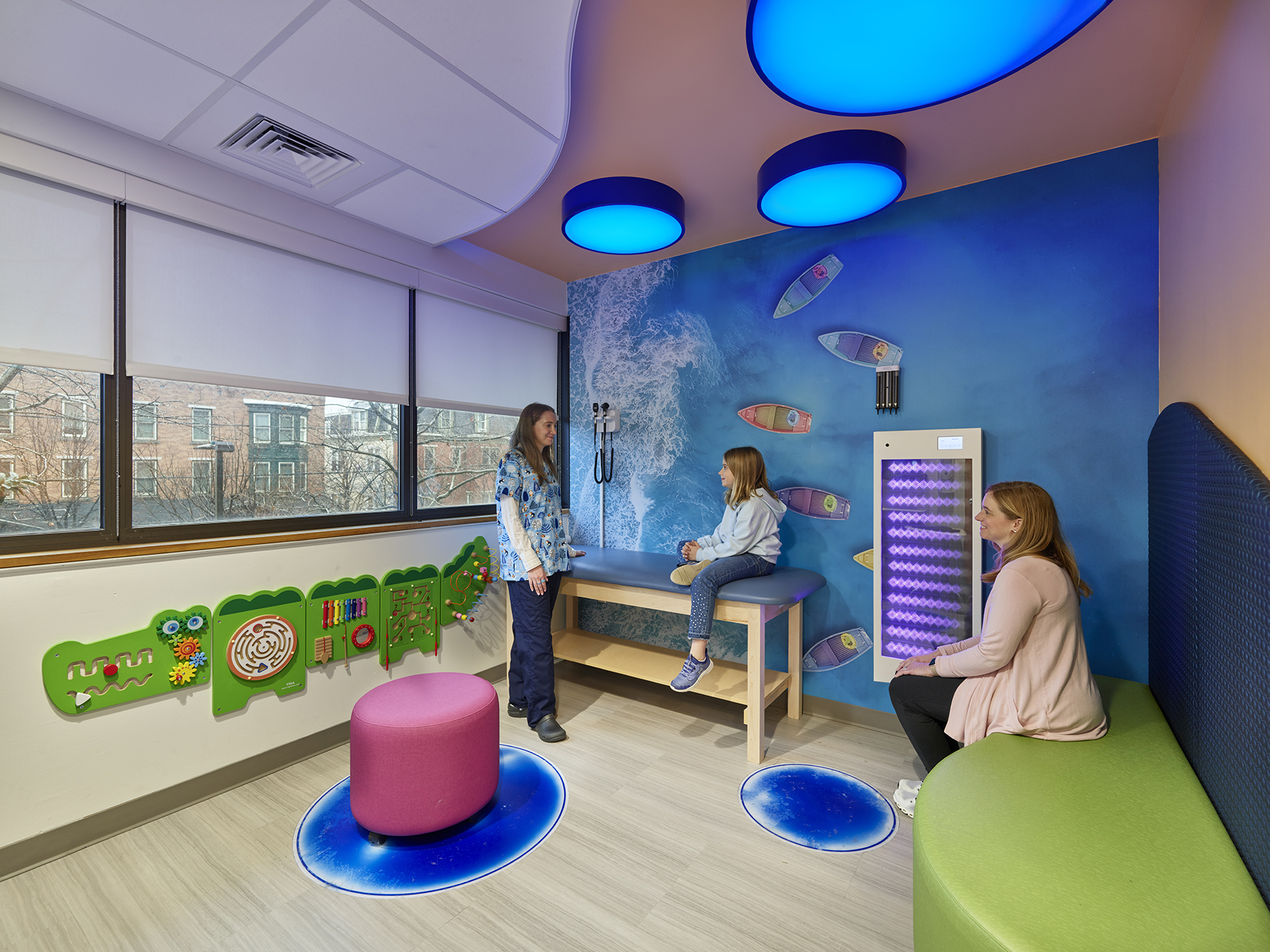 Colorful wellness room with a calming mural of the ocean, large windows, and comfortable spaces to sit.