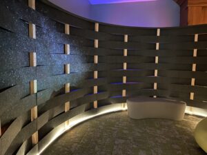 A sensory space with soft curved walls, and low lighting, and soft curved bench seats.