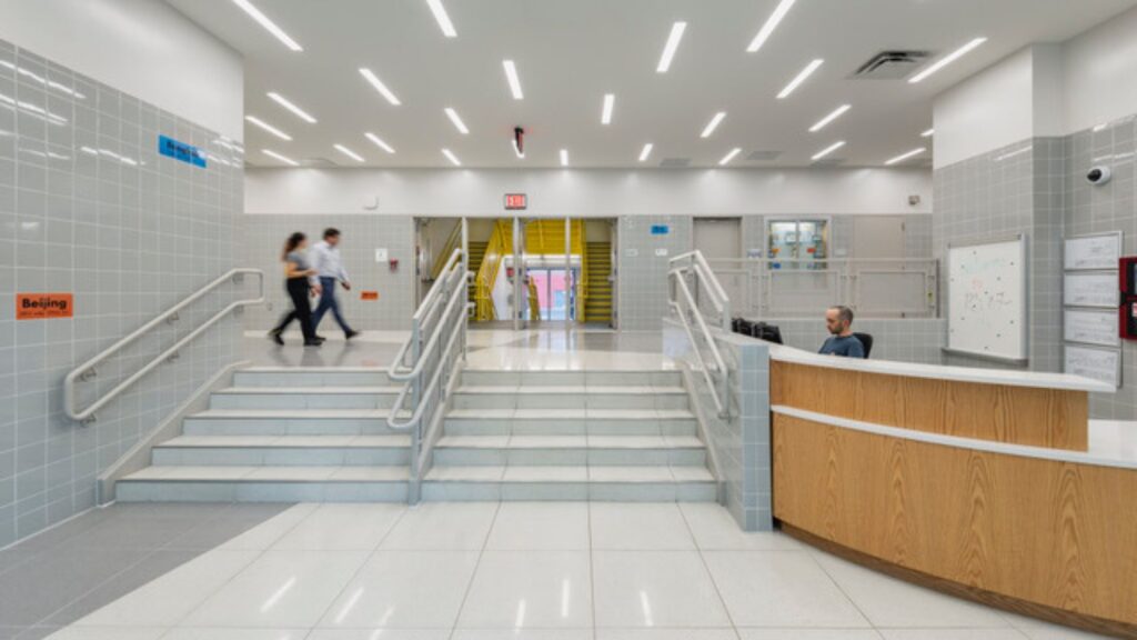 The project reframes the campus around universal accessibility, all-electric building systems and a contemporary gymnasium-auditorium, while modernizing circulation and shared spaces within the existing 1930s structure.