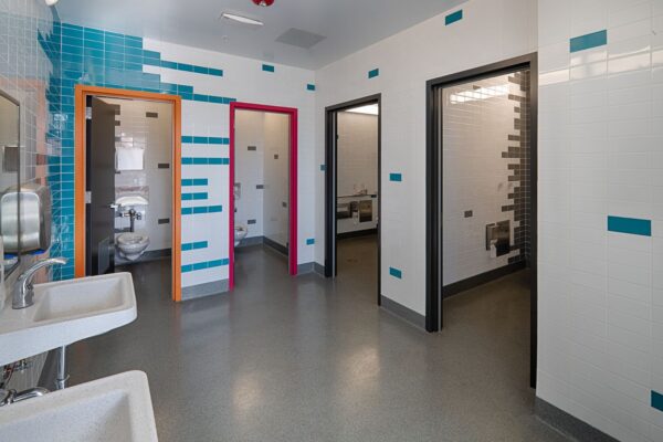 The inclusive restroom at Freestyle Academy in the Mountain View Los Altos Unified High School District shows that these layouts can often be achieved within the same building footprint as traditional restrooms, making them feasible for both new construction and renovation projects.