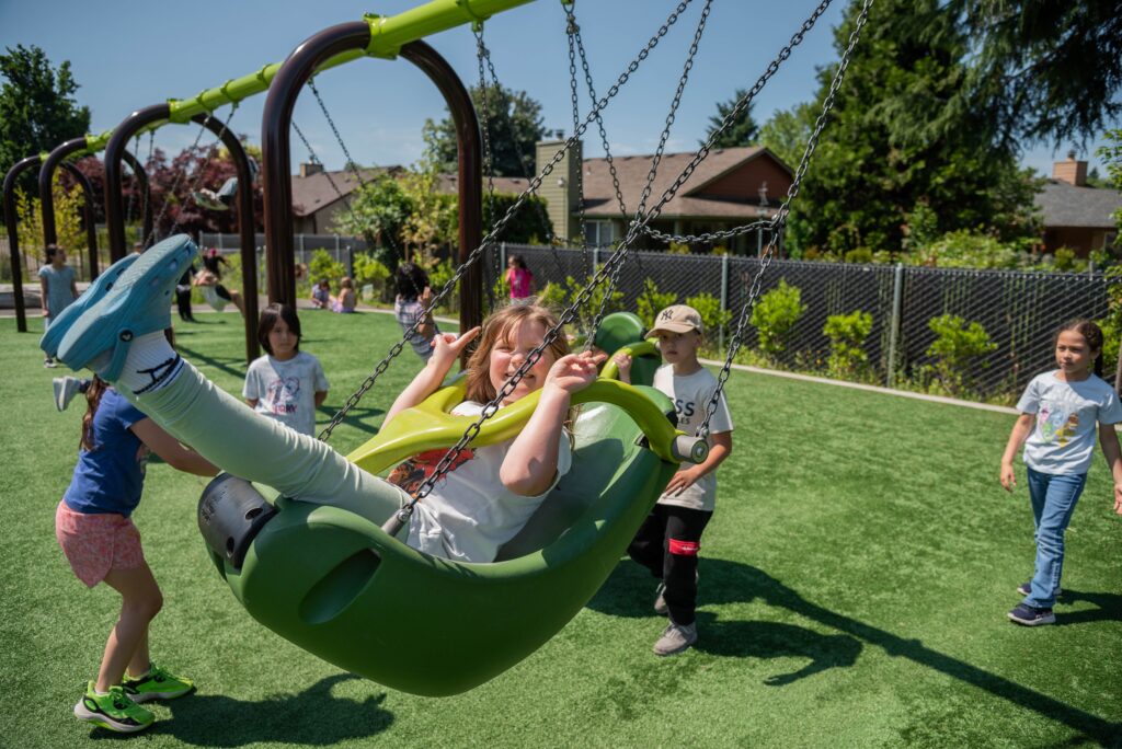 children playing on swings at an inclusive playground